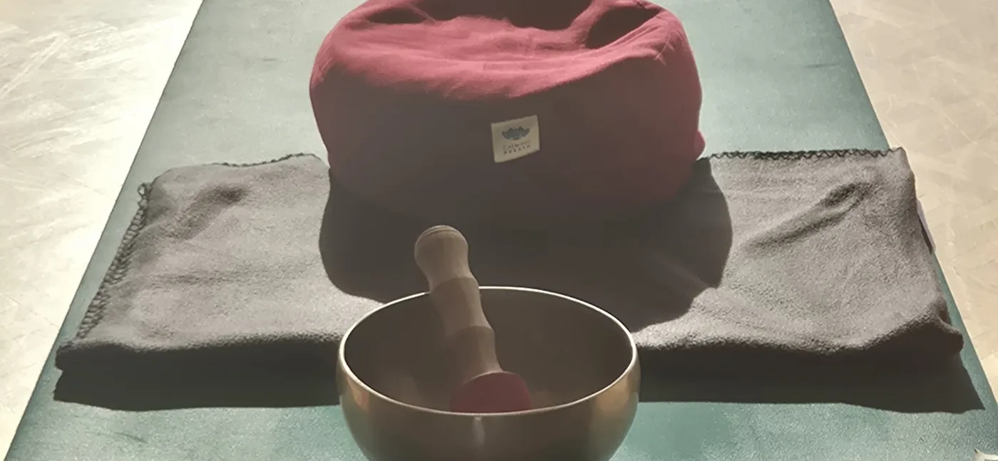 Yogamatte mit Meditationskissen und Klangschale im Studio